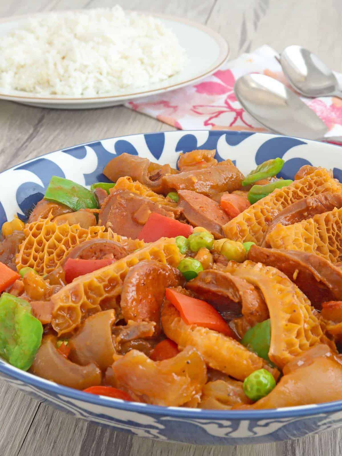 ox tripe stew with garbanzo beans, green peas, and bell peppers in a blue serving bowl