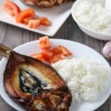 fried butterflied milkfish on a white plate with steamed rice and chopped tomatoes
