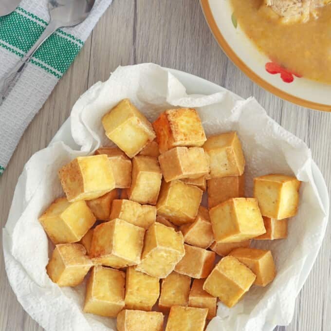 crispy tofu cubes in paper lined bowl