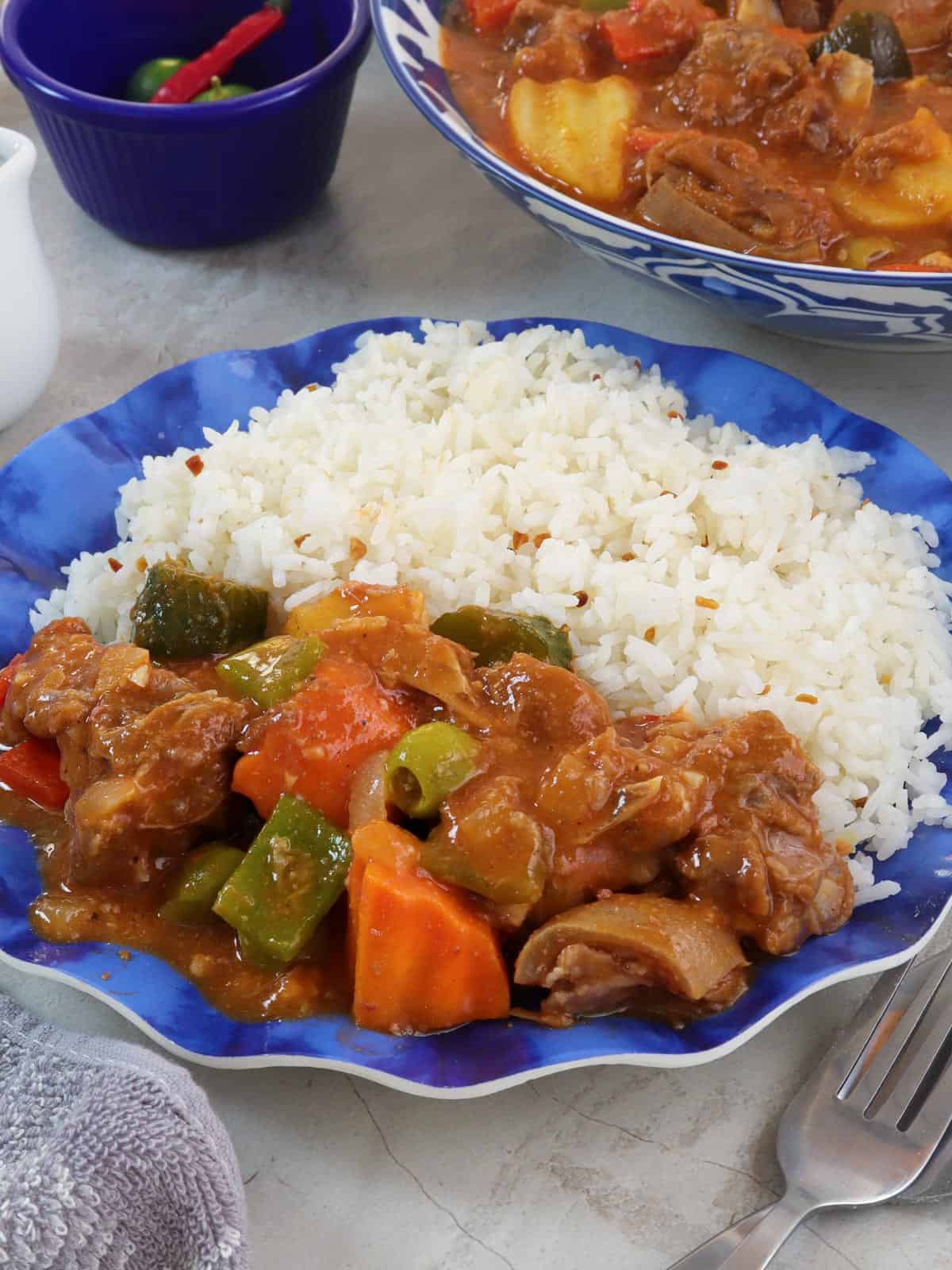 kambing caldereta with steamed rice on a blue plate