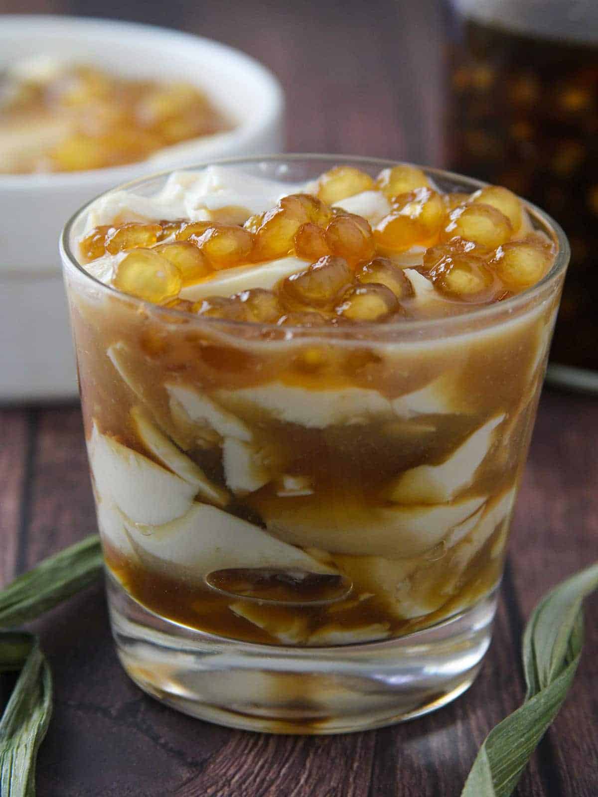Taho in a clear glass with brown syrup and sago