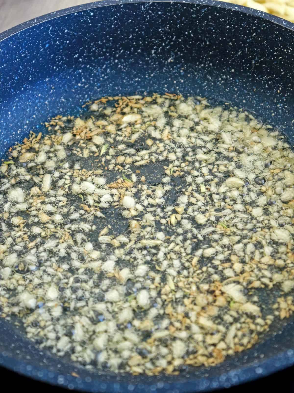 frying garlic bits in oil in a pan