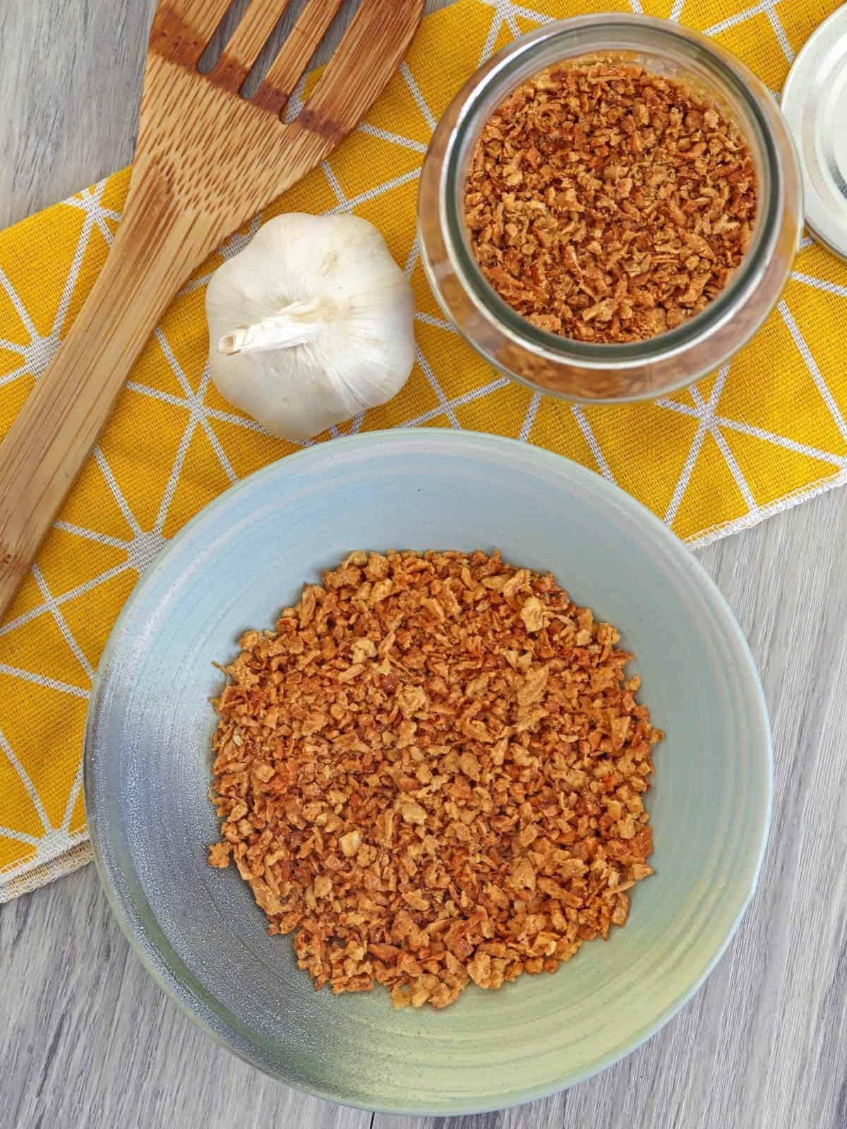 toasted garlic bits in a bowl with a whole garlic head on the side