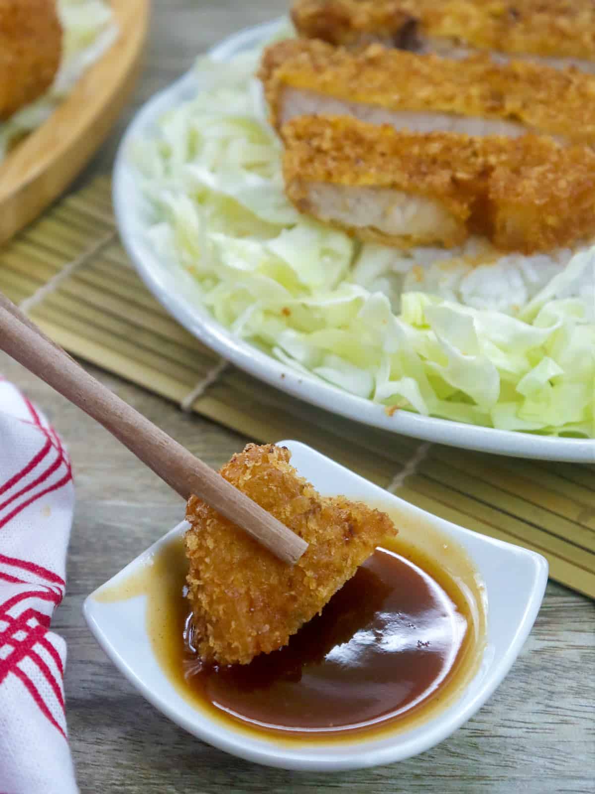 dipping slice of breaded pork chop in tonkatsu sauce