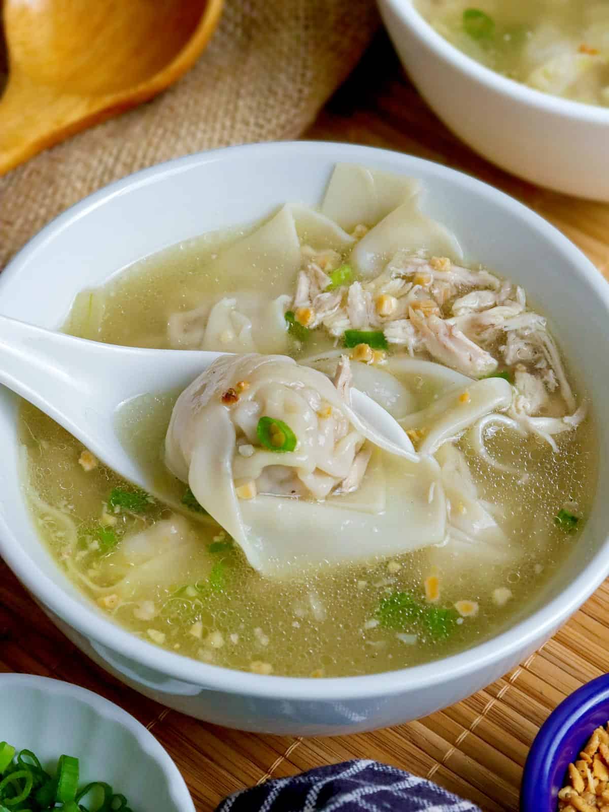 eating Filipino wonton soup from a white bowl