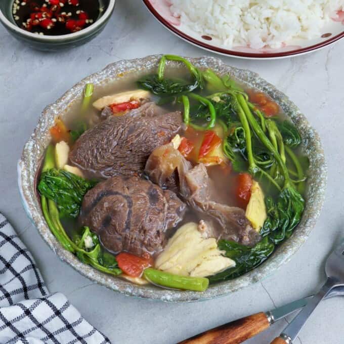 Sinigang na Baka sa Bayabas in a serving bowl with a plate of steamed rice and a dish of patis on the side