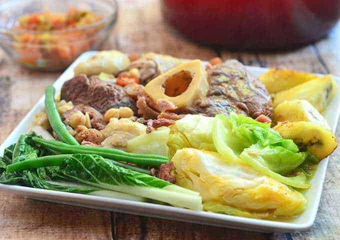 Cocido with slow-cooked meat, sausages, and vegetables and served with berenjana sauce on the side.