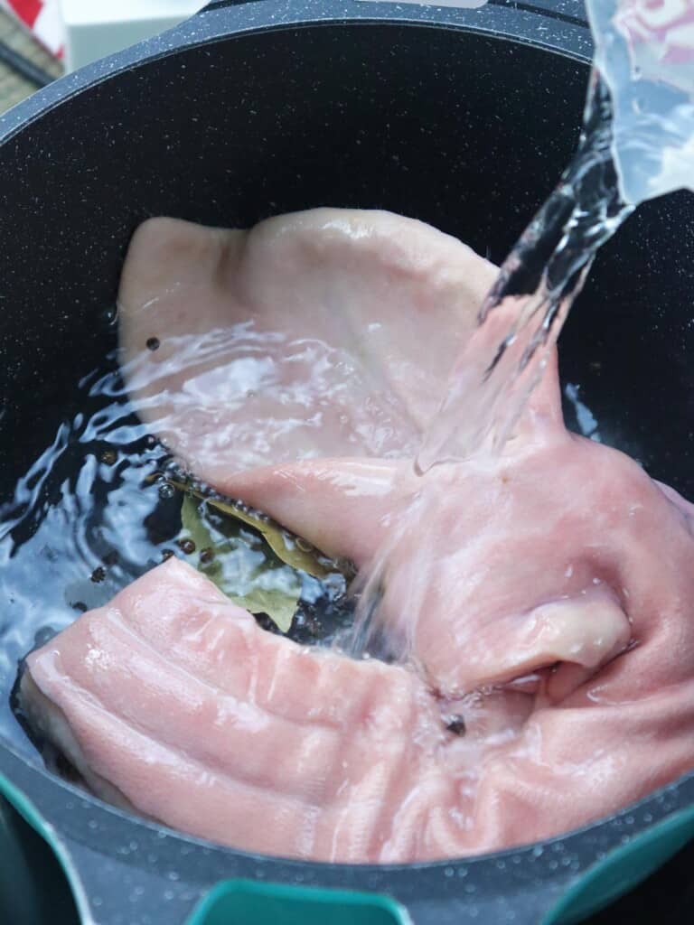 covering pork face with water in a pot