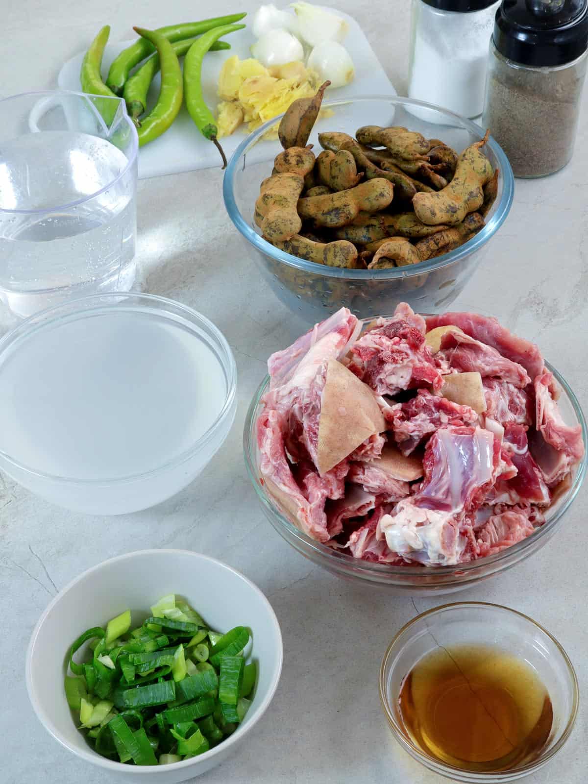 cut goat meat, green tamarind, chili peppers, vinegar, fish sauce, and green onions in bowls