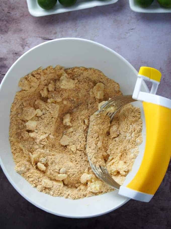 cutting butter into graham crust in a bowl using a pastry cutter