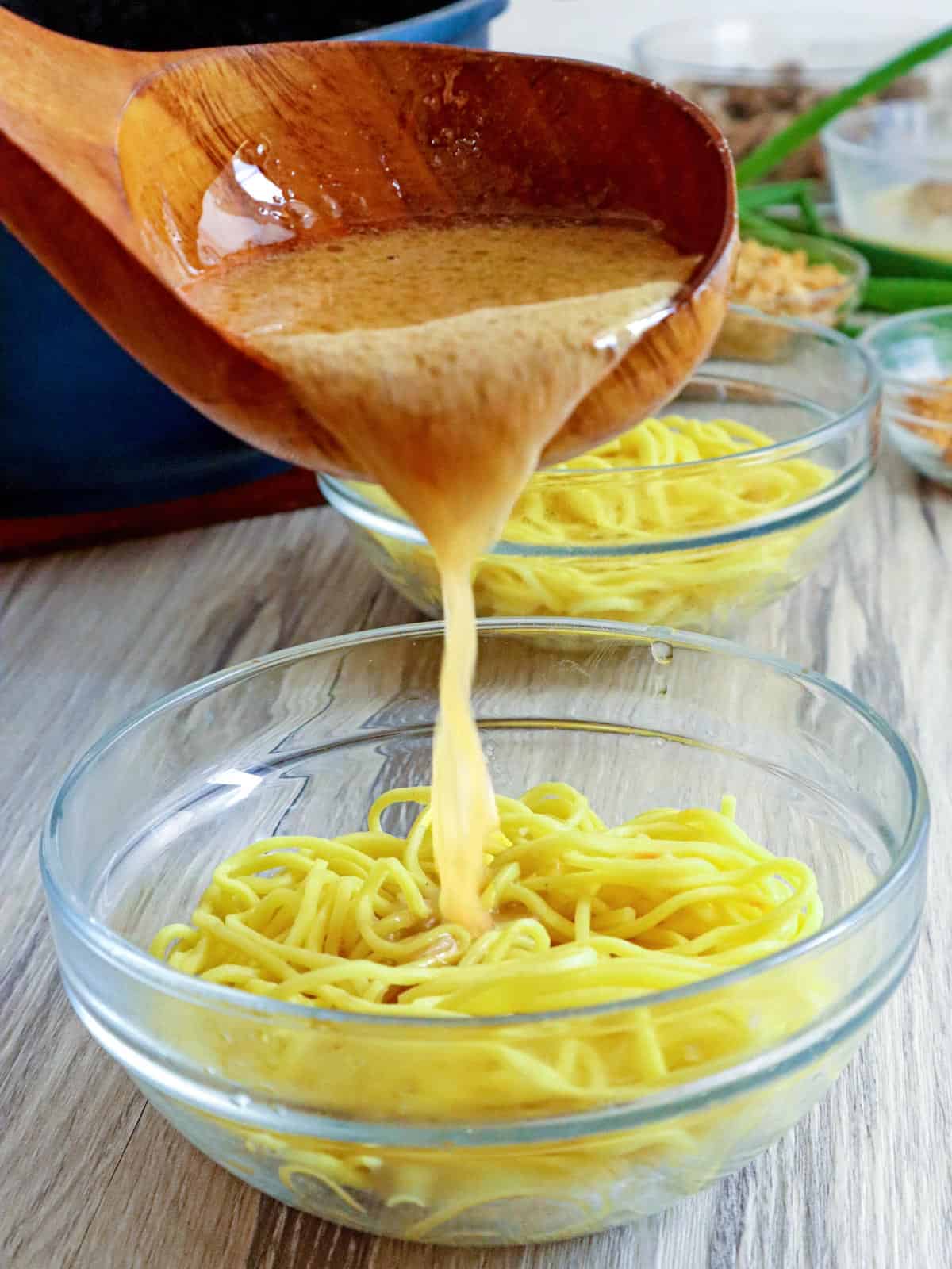 pouring homemade broth over a bowl of miki noodles 