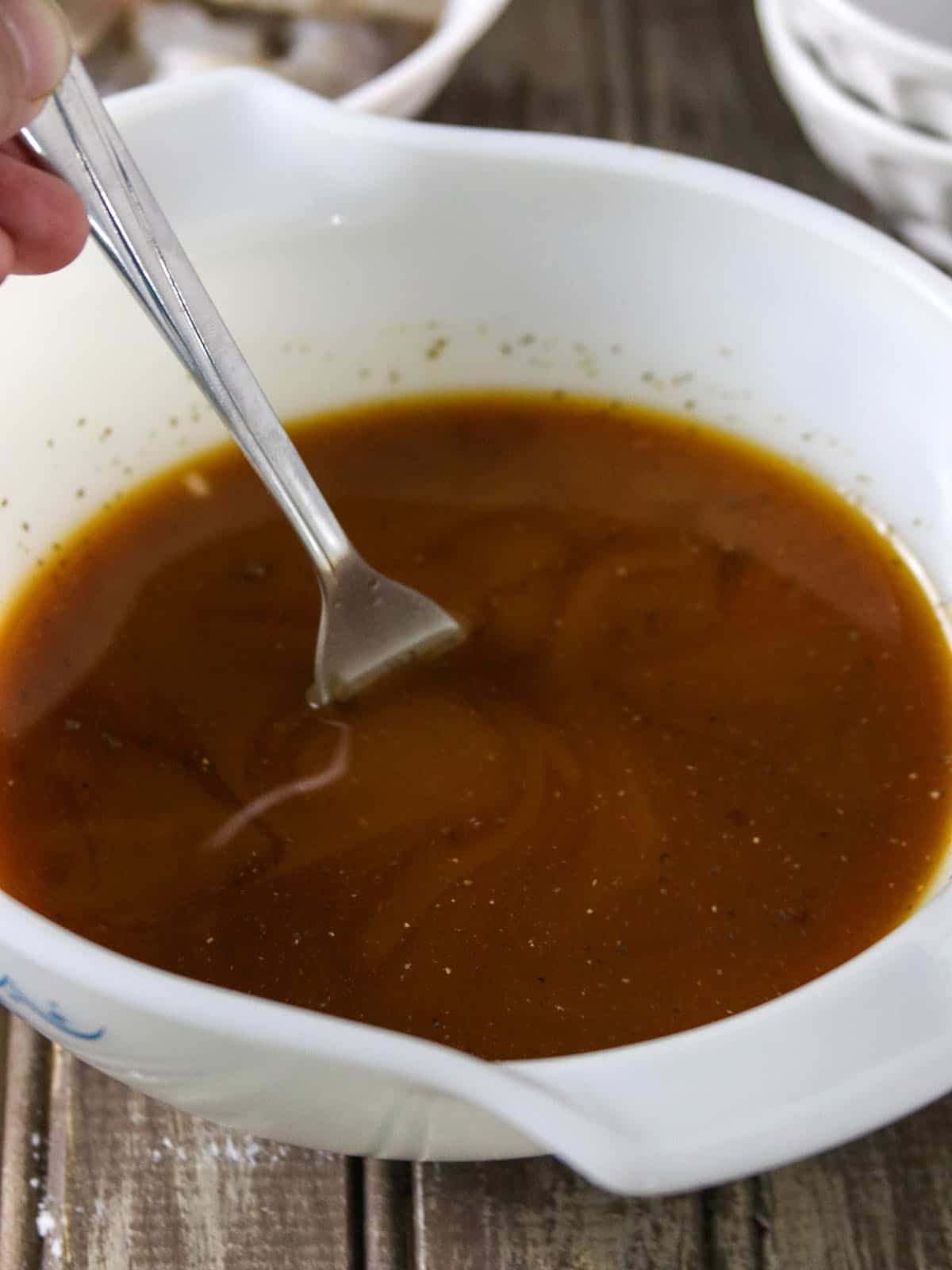 stirring stir fry sauce in a white bowl