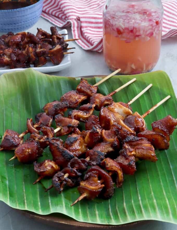 BBQ Pork Ears on a banana leaf lined plate with spicy vinegar on the side