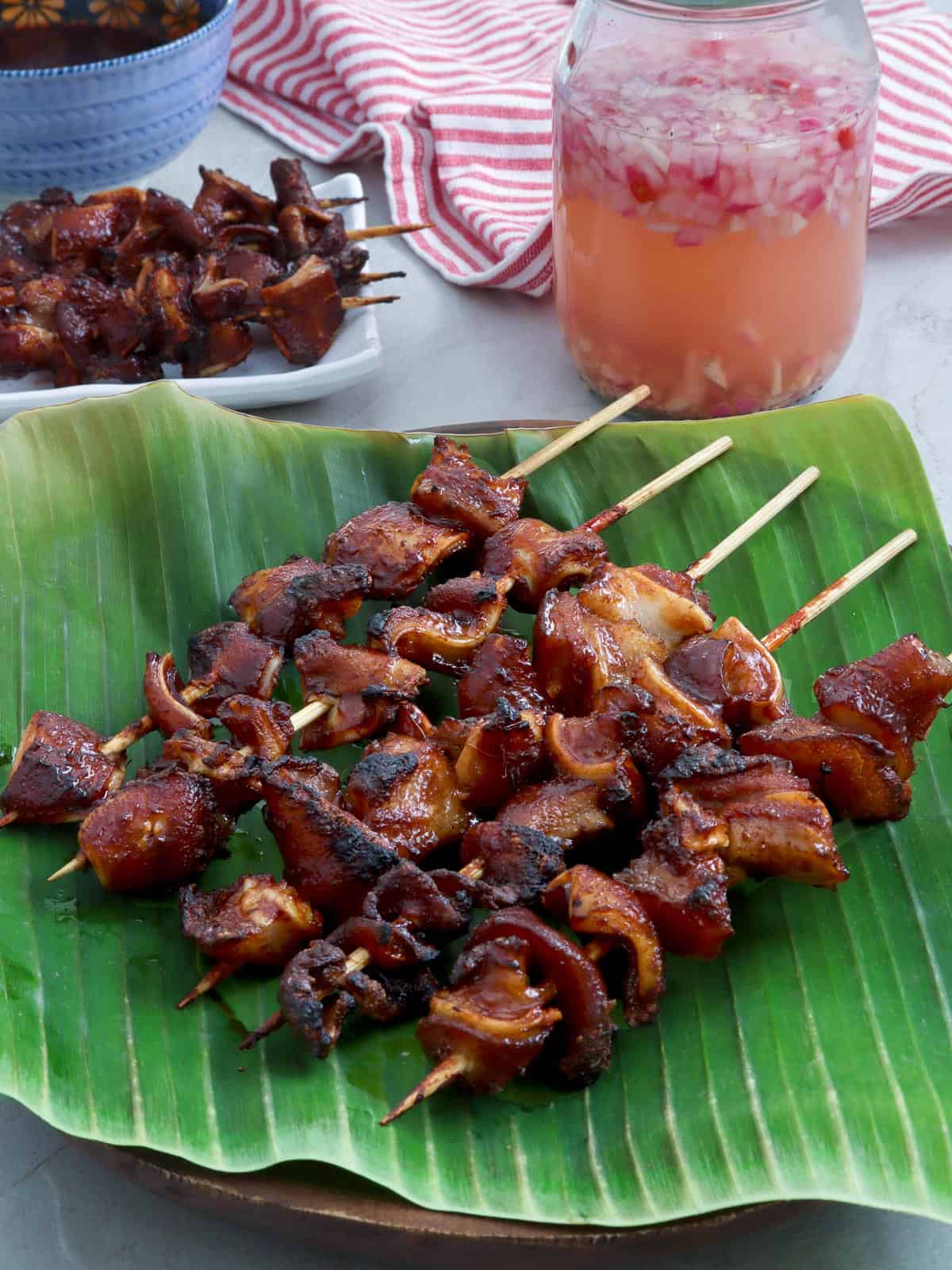 BBQ Pork Ears on a banana leaf lined plate with spicy vinegar on the side