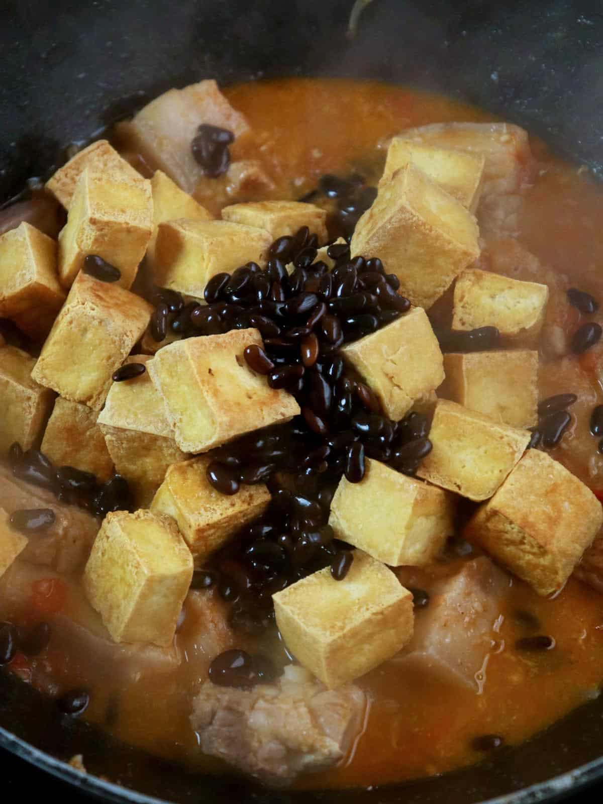 cooking pork and tofu with tomatoes and salted black beans in a pan