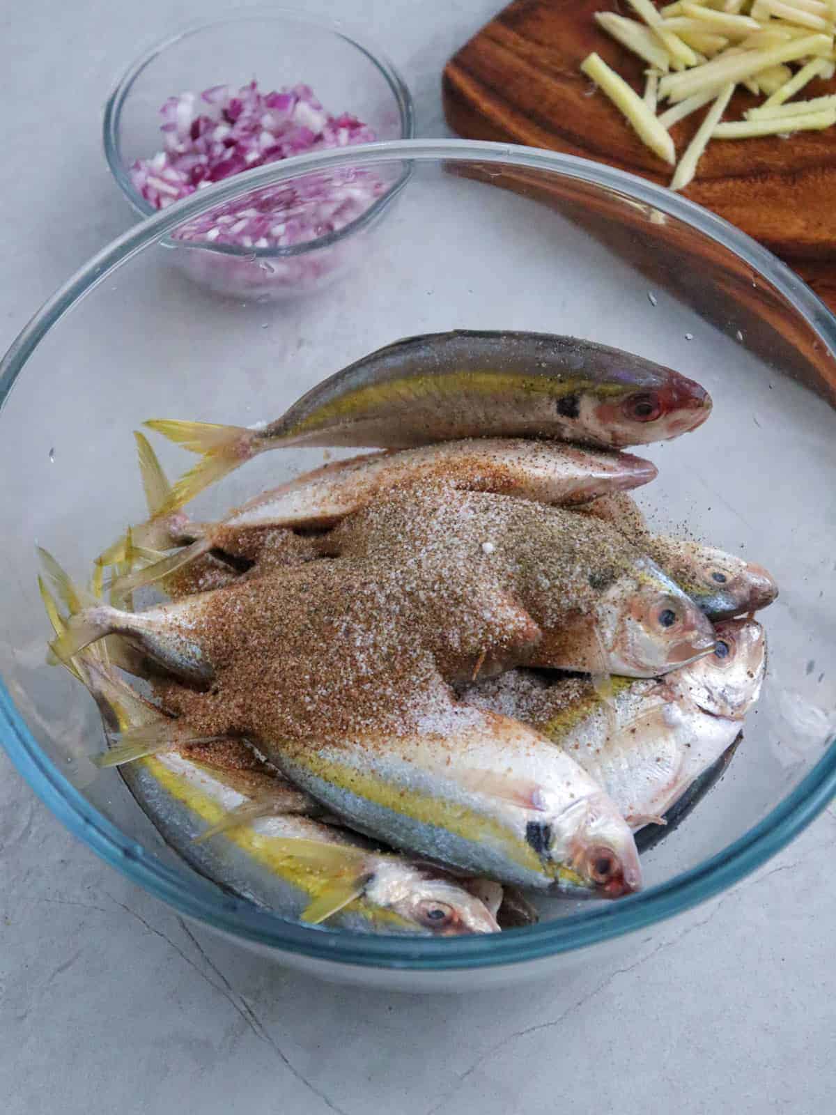 seasoning yellowtail scad with tamarind powder in a clear bowl