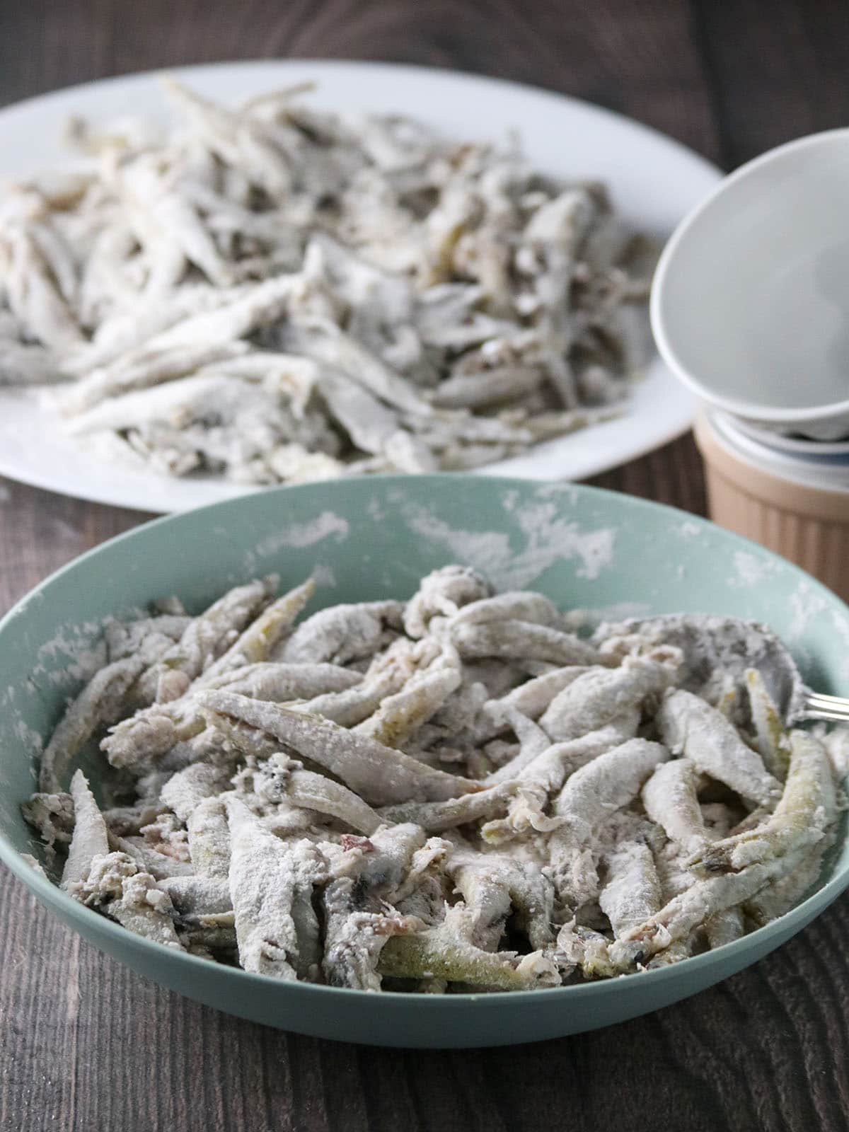smelt fish coated in cornstarch and flour mixture in a bowl