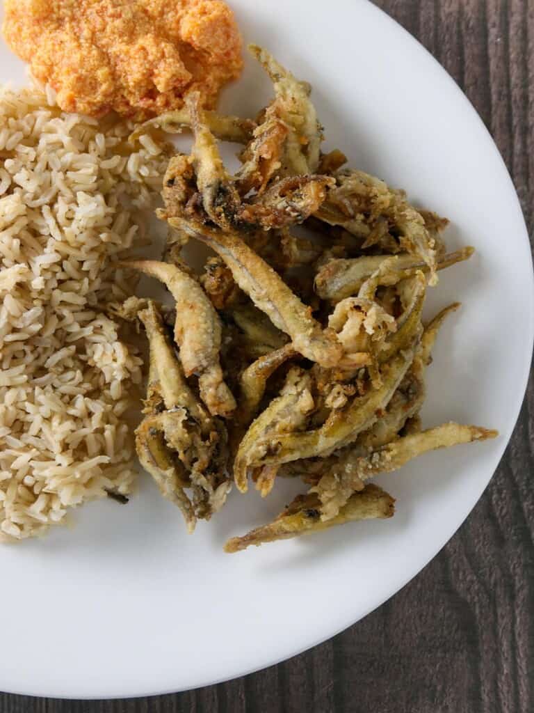 crispy smelt fish and brown rice on a white plate