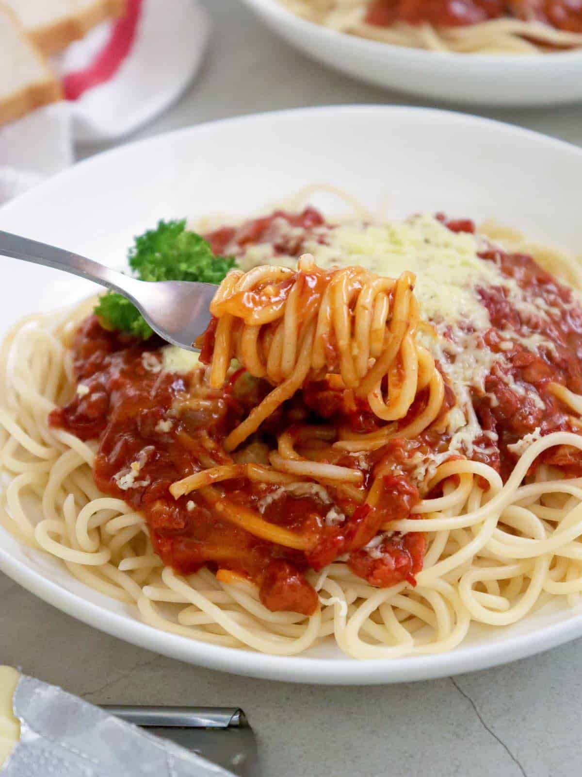 eating Corned Beef Spaghetti on a white serving plate with a fork