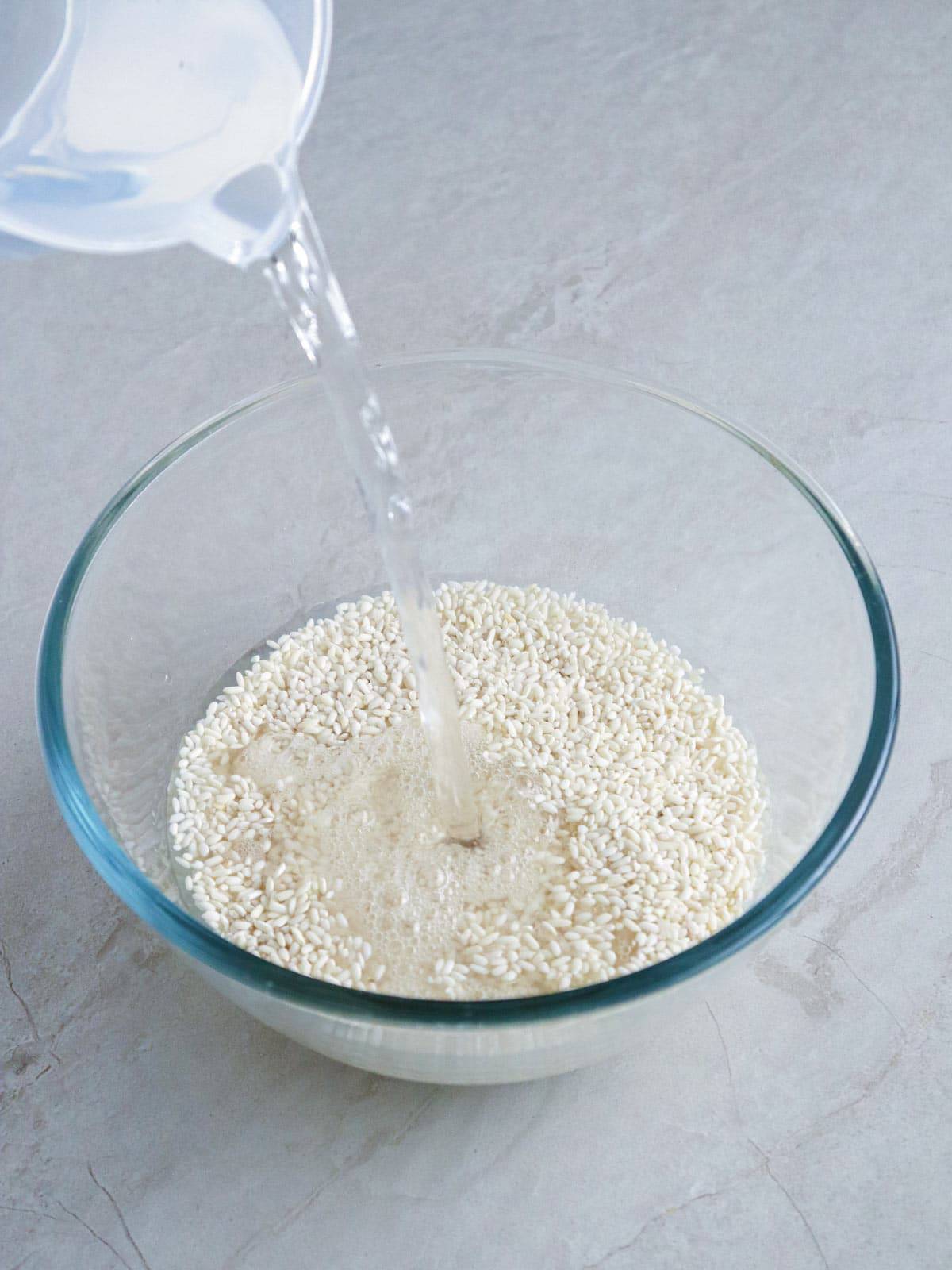 pouring water to glutinous rice in a glass bowl