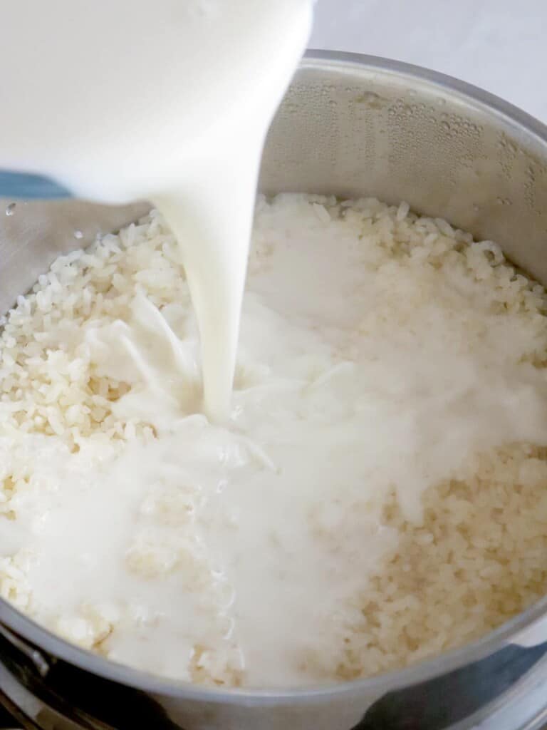 pouring coconut milk to steamed glutinous rice in a pot