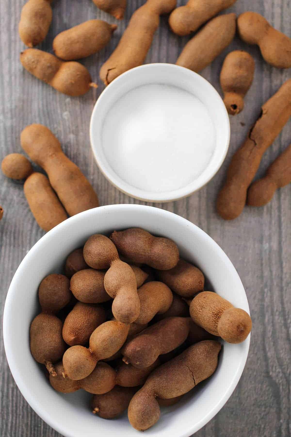 fresh tamarind pods and sugar in bowls