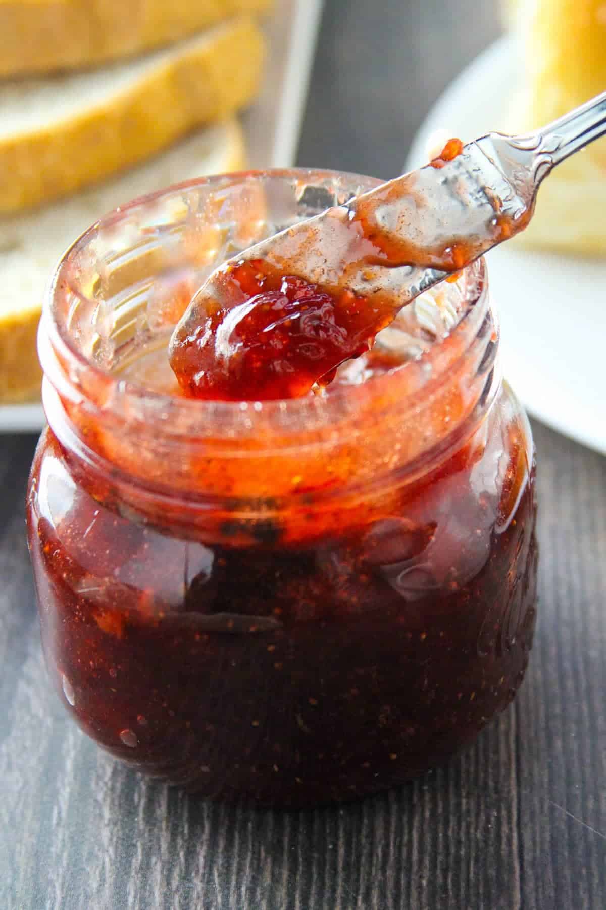 Serving Black Pepper Strawberry Jam from mason jar with a spoon
