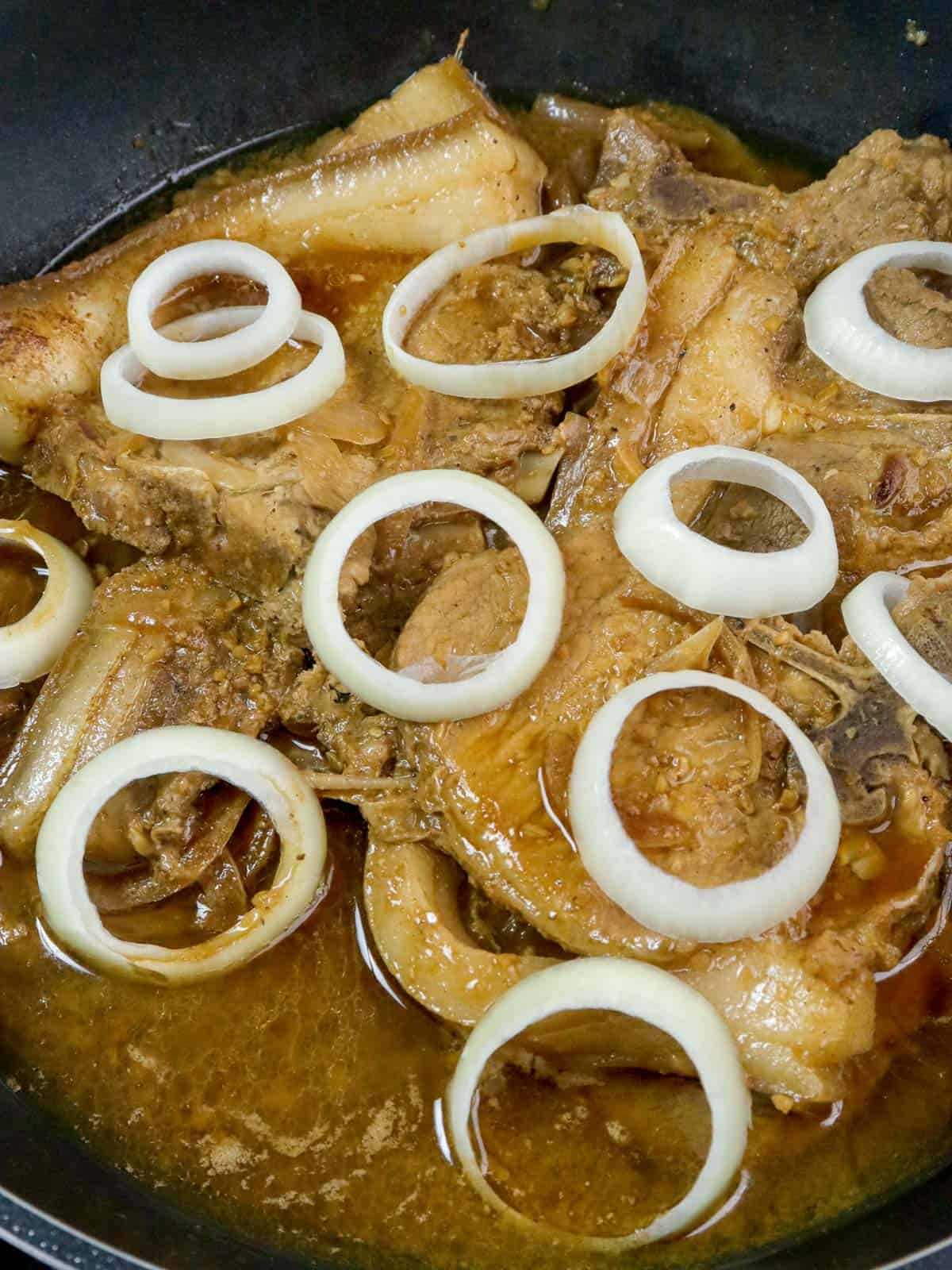 Filipino pork chops a la bistek with onions in a pan