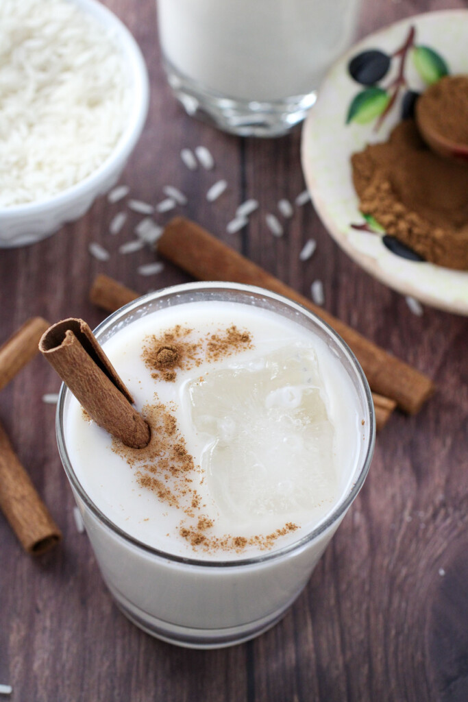 horchata in a glass with ice and cinnamon stick