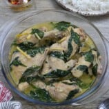 Pinatisang Manok in a glass serving bowl with a plate of steamed rice in the background.