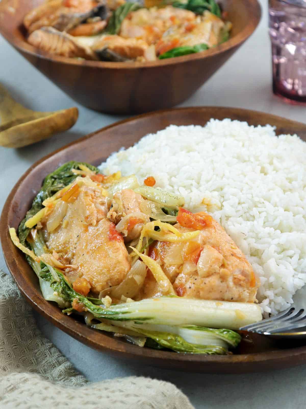 salmon belly in oyster with pechay served with steamed rice on a wooden plate