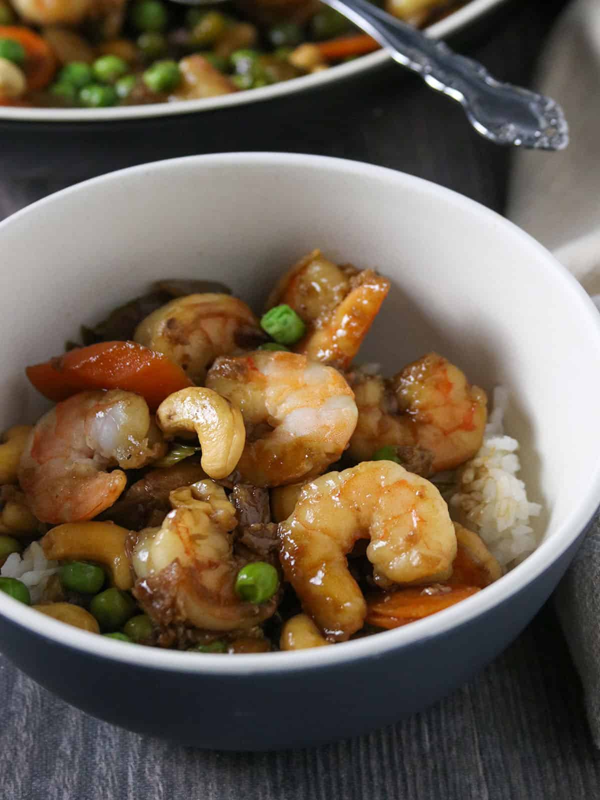 shrimp green peas and cashew stir-fry in a bowl over steamed rice