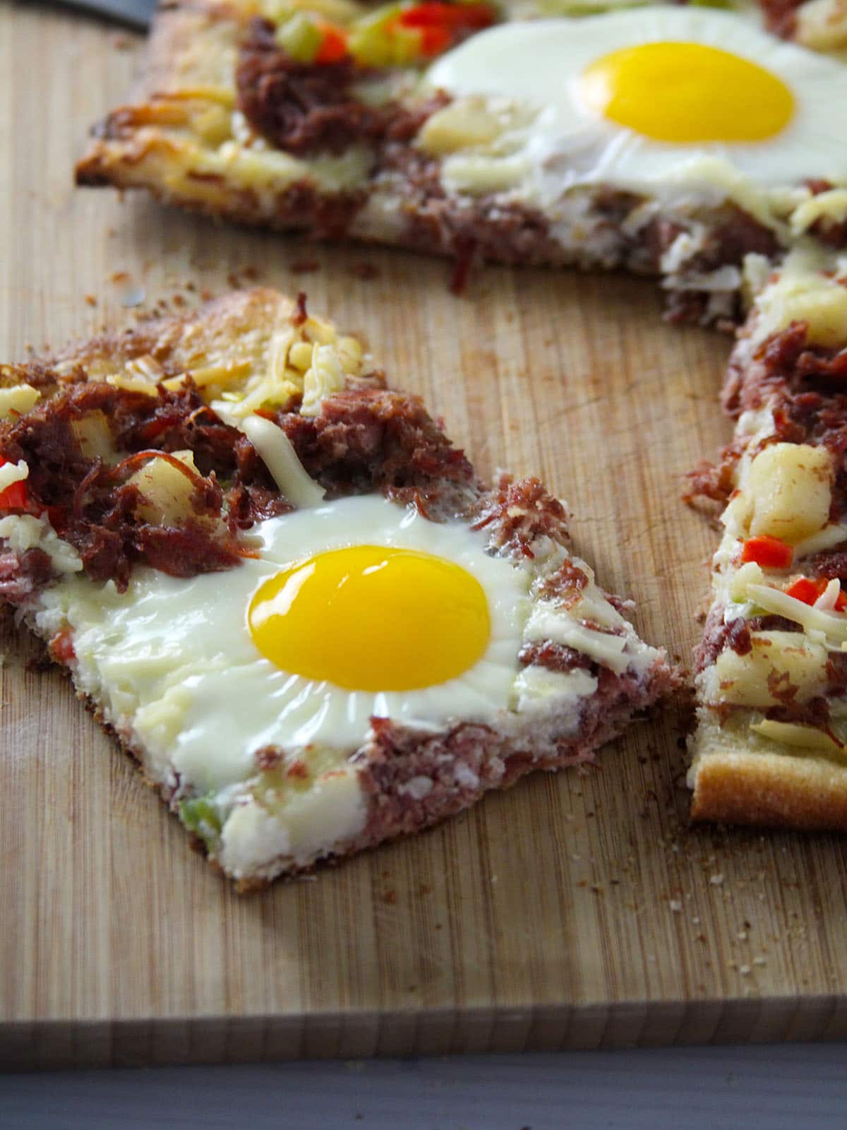 slice of breakfast pizza on a cutting board