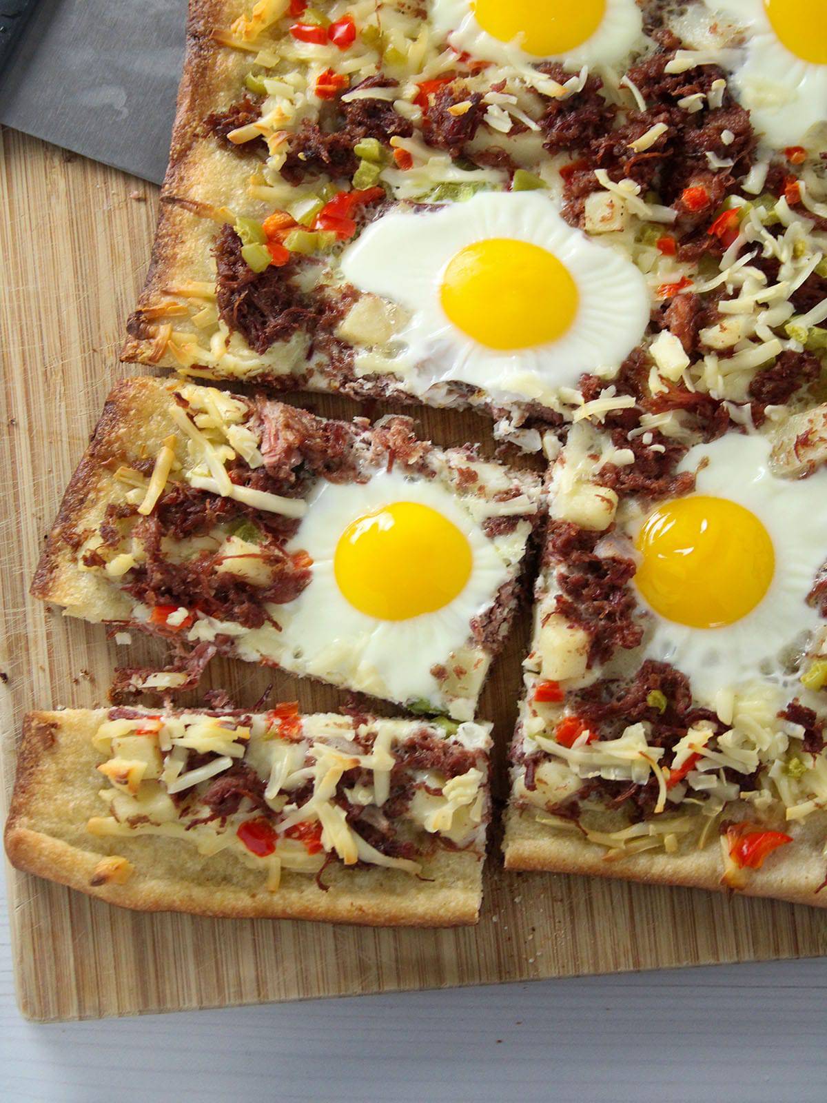 sliced breakfast pizza with egg and corned beef hash topping
