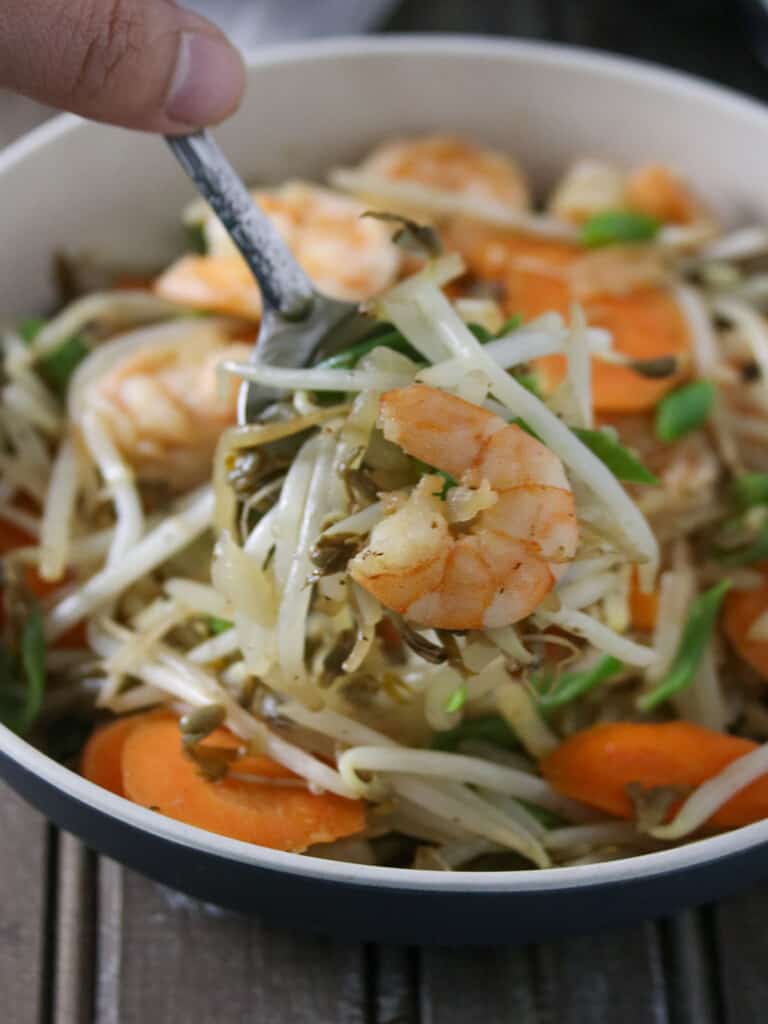 serving bean sprouts stir-fry with a spoon from a bowl