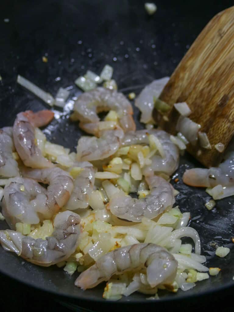sauteing shrimp with garlic and onions in a pan