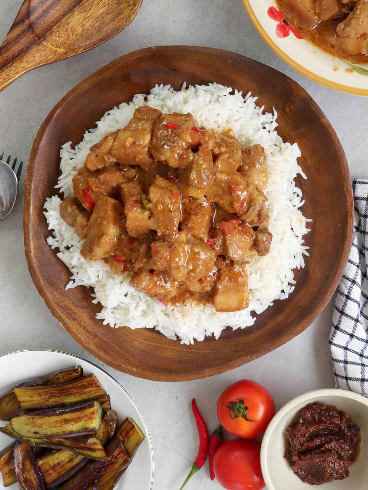 Pork Binagoongan with coconut milk over rice on a wooden plate