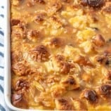 freshly baked bread pudding with raisins, pineapple, and shredded coconut in a white pan