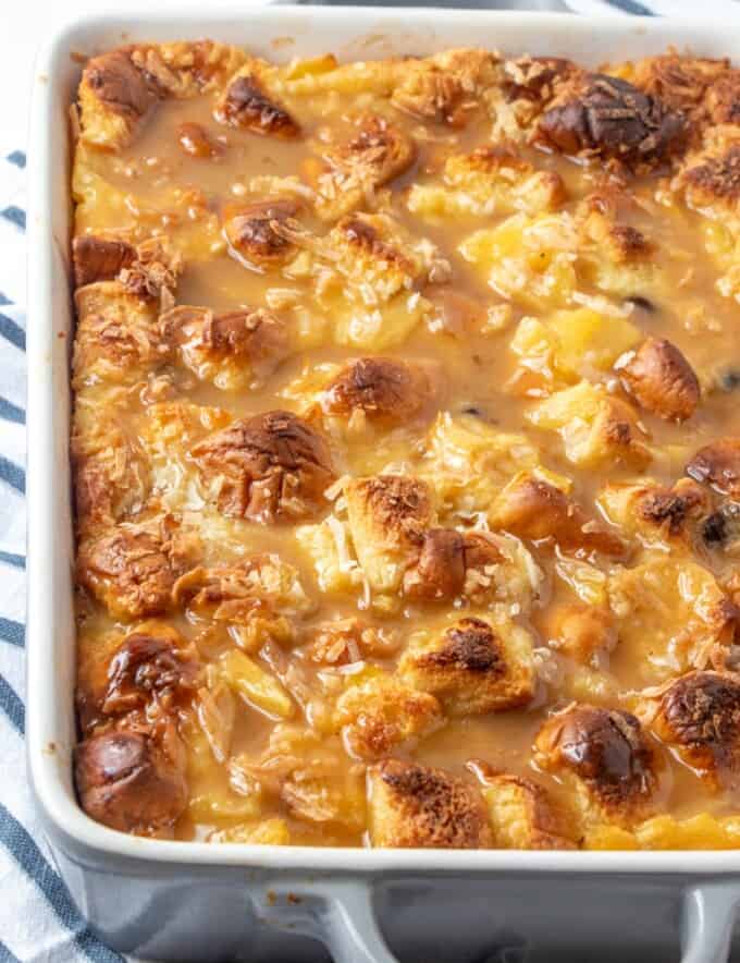 freshly baked bread pudding with raisins, pineapple, and shredded coconut in a white pan