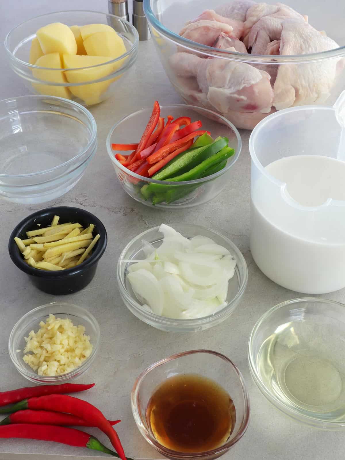 chicken, potatoes, ginger, garlic, onions, coconut cream, bell peppers, fish sauce, oil, chili peppers, water in bowls