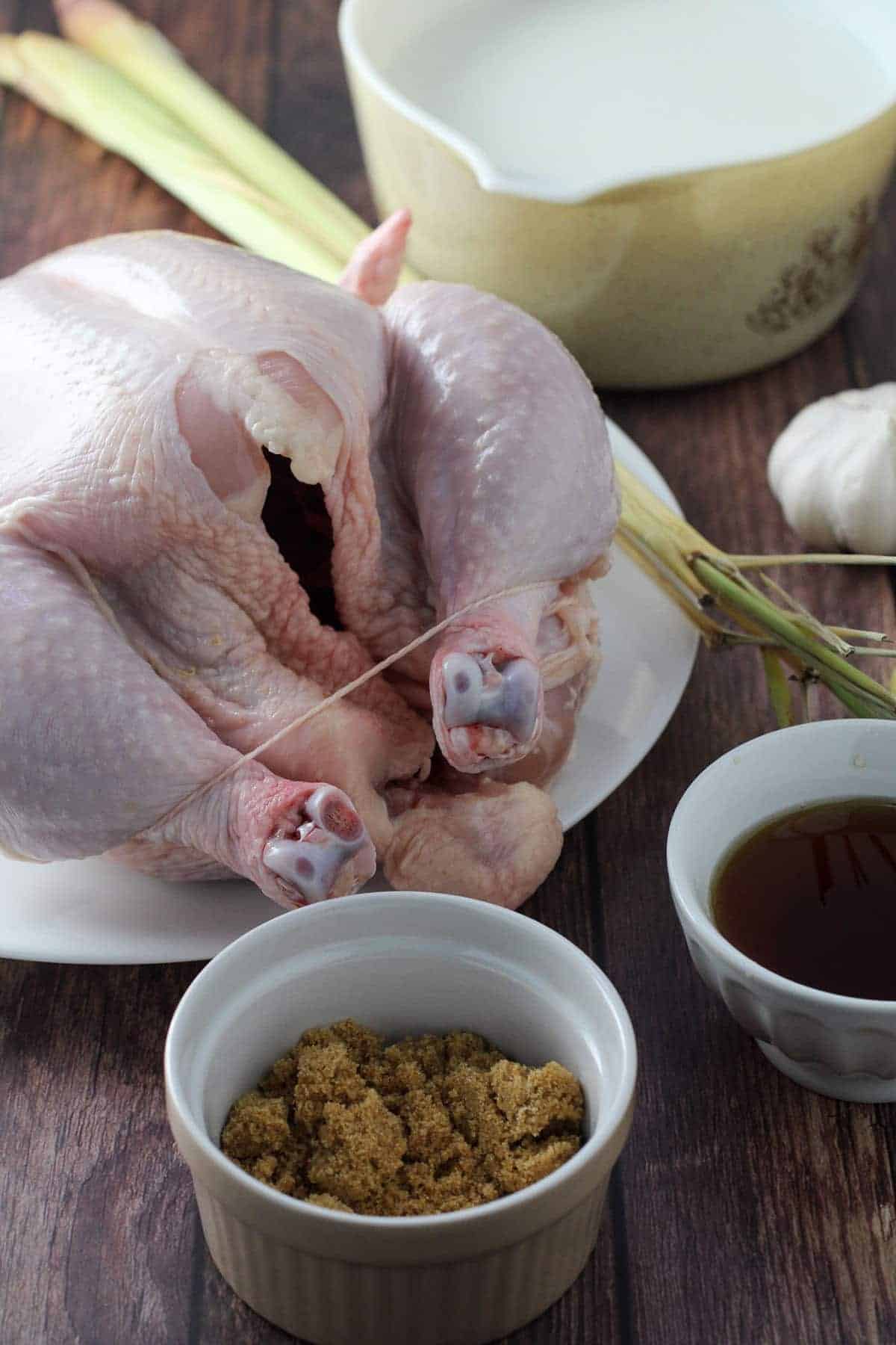 whole chicken, coconut milk, brown sugar, lemongrass, garlic, soy sauce on wooden board