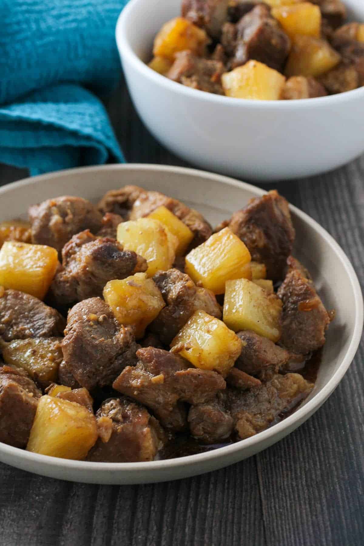 pork adobo with pineapple in a white serving bowl