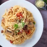 top view of spaghetti carbonara with bacon on a white plate