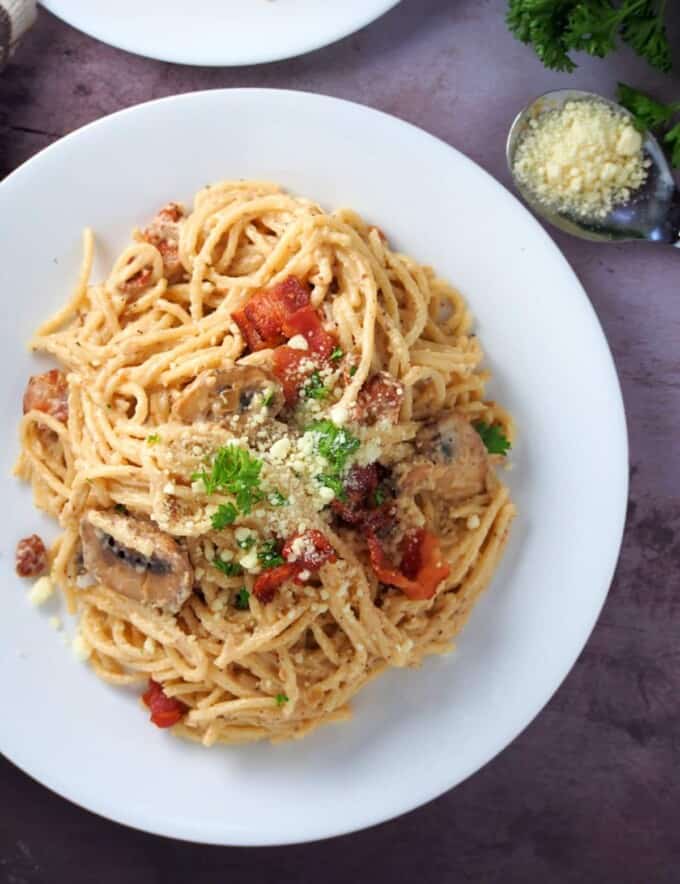 top view of spaghetti carbonara with bacon on a white plate