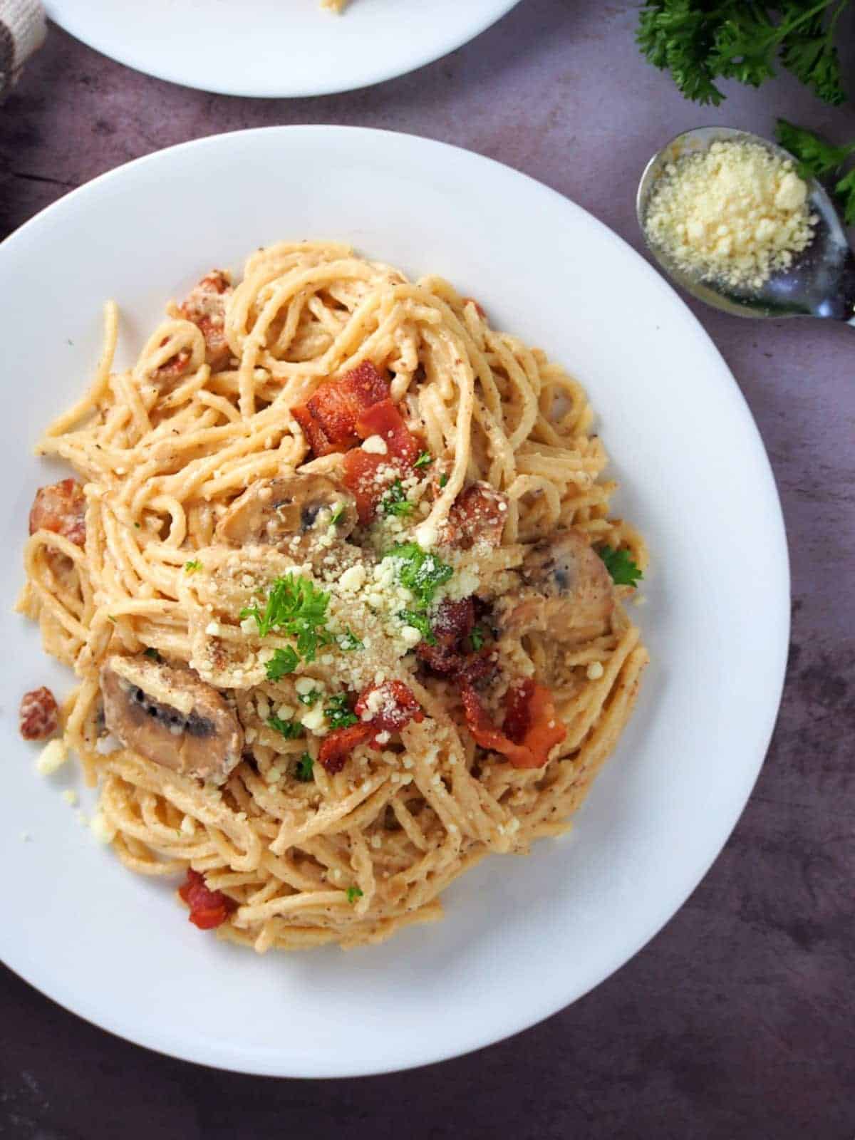 top view of spaghetti carbonara with bacon on a white plate