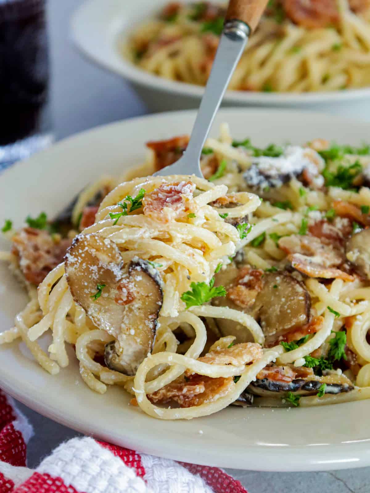 eating Filipino-style pasta with a fork on a white plate.