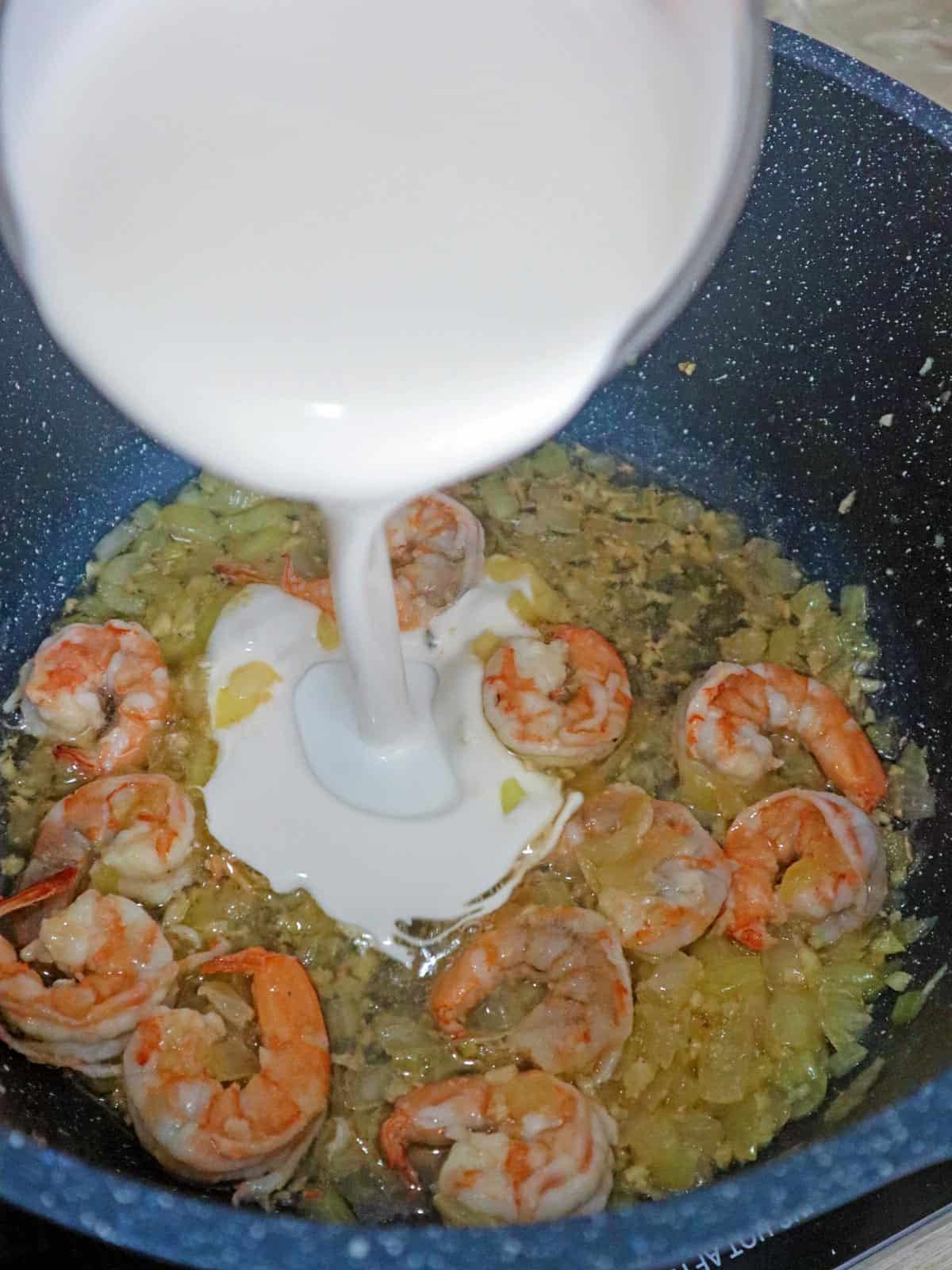 pouring coconut milk to sauteed shrimp