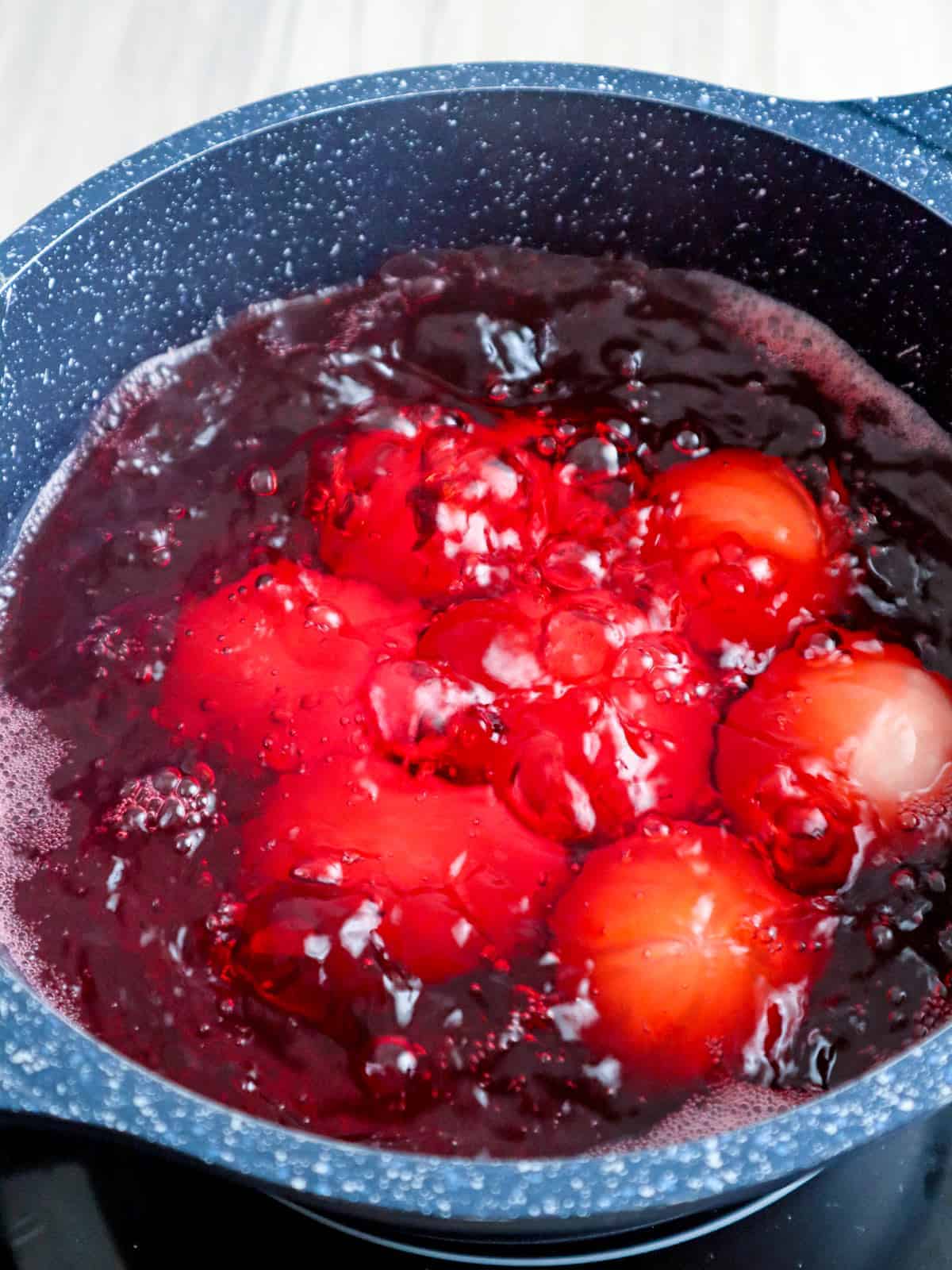 boiling salted eggs in water with red food color in pot