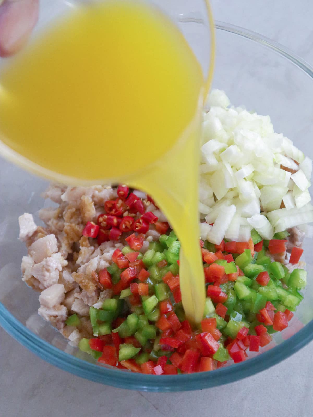 pouring calamansi juice to a bowl of sisig