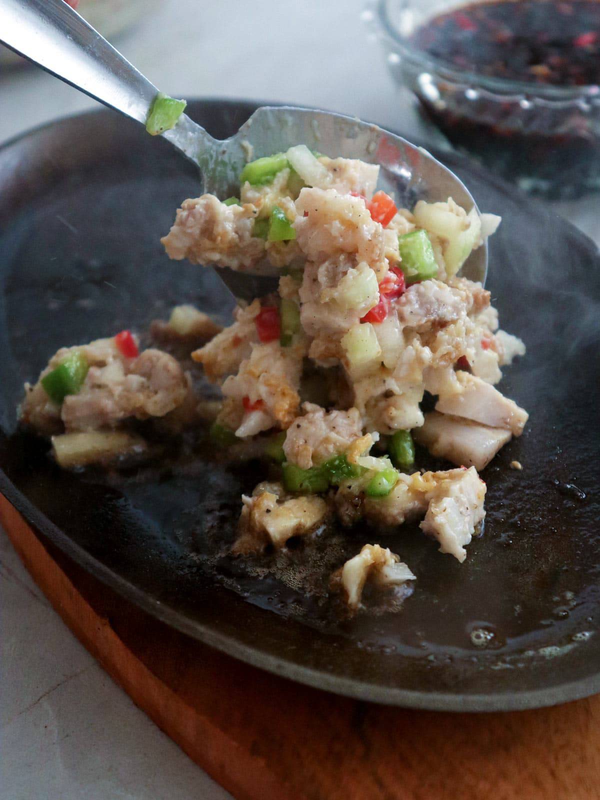putting sisig on a sizzling plate